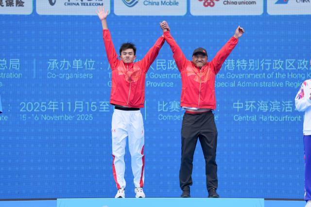 (251115) -- HONG KONG, Nov. 15, 2025 (Xinhua) -- Gold medalist Fan Junjie (L) of Henan celebrates with his coach during the awarding ceremony for the men's individual triathlon at China's 15th National Games in Hong Kong, south China, Nov. 15, 2025. (Xinhua/Wu Lu)