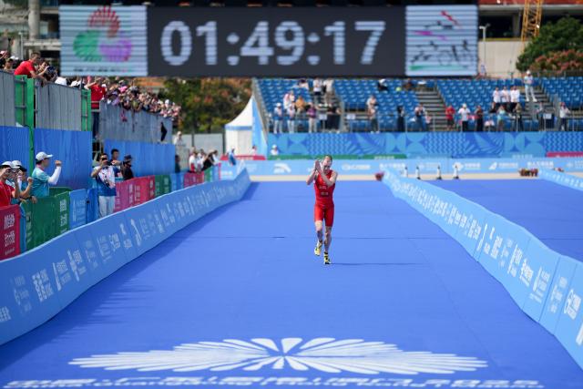 (251115) -- HONG KONG, Nov. 15, 2025 (Xinhua) -- Oscar Coggins of Hong Kong greets the spectators while crossing the finish line during the men's individual triathlon at China's 15th National Games in Hong Kong, south China, Nov. 15, 2025. (Xinhua/Wu Lu)