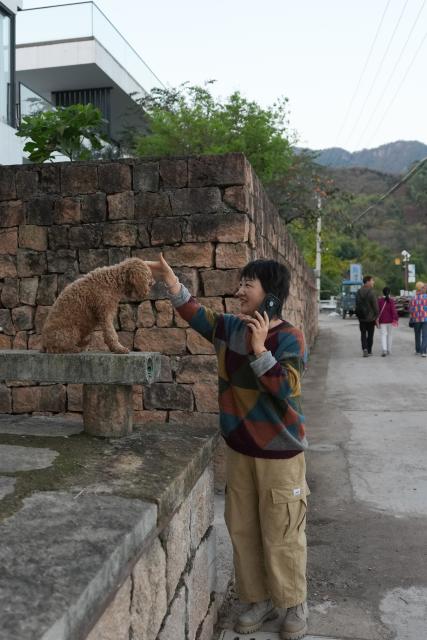(251115) -- NINGBO, Nov. 15, 2025 (Xinhua) -- Xu Xiaofeng, a homestay owner, plays with a dog in Dongshan Village of Xikou Town in Ningbo City, east China's Zhejiang Province, Nov. 13, 2025.
  With its prime geographical location, rich resources and improved infrastructure, Dongshan Village has in recent years witnessed rapid development in tourism through rural collective management program.
   Young people involved in the program have rooted themselves here to run homestays and cafes, using their professional expertise to activate rural resources and truly benefit the villagers. (Xinhua/Huang Zongzhi)