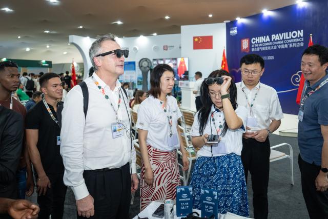(251115) -- BELEM, Nov. 15, 2025 (Xinhua) -- Guests try a China-made smart device at the China Pavilion during the 30th United Nations climate change conference in Belem, Brazil, Nov. 12, 2025. The 30th United Nations climate change conference, commonly known as COP30, opened Monday in Belem, Brazil. Displays of Chinese cultural products, green technologies, and innovations attracted attention of the attendees during the conference. (Xinhua/Wang Tiancong)