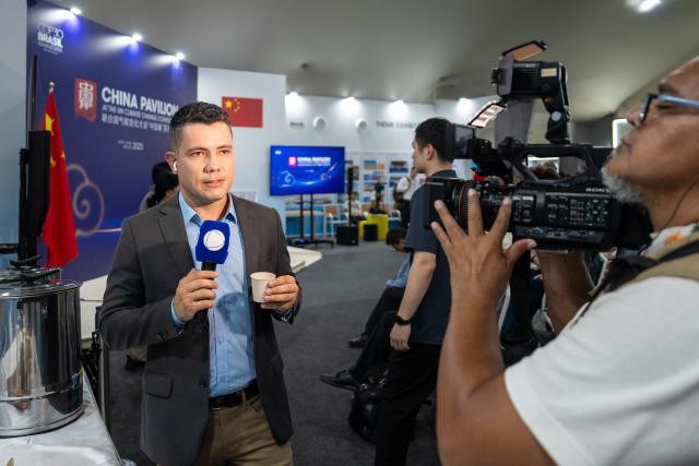 (251115) -- BELEM, Nov. 15, 2025 (Xinhua) -- A journalist covers Chinese tea at the China Pavilion during the 30th United Nations climate change conference in Belem, Brazil, Nov. 12, 2025. The 30th United Nations climate change conference, commonly known as COP30, opened Monday in Belem, Brazil. Displays of Chinese cultural products, green technologies, and innovations attracted attention of the attendees during the conference. (Xinhua/Wang Tiancong)