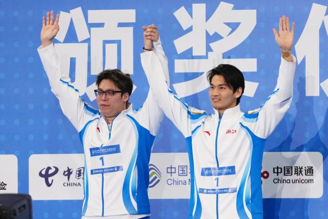 (251115) -- SHENZHEN, Nov. 15, 2025 (Xinhua) -- Gold medalist Xu Jiayu of Zhejiang and his coach wave during the awarding ceremony for the men's 200m backstroke of swimming at China's 15th National Games in Shenzhen, south China's Guangdong Province, Nov. 15, 2025. (Xinhua/Xue Yuge)