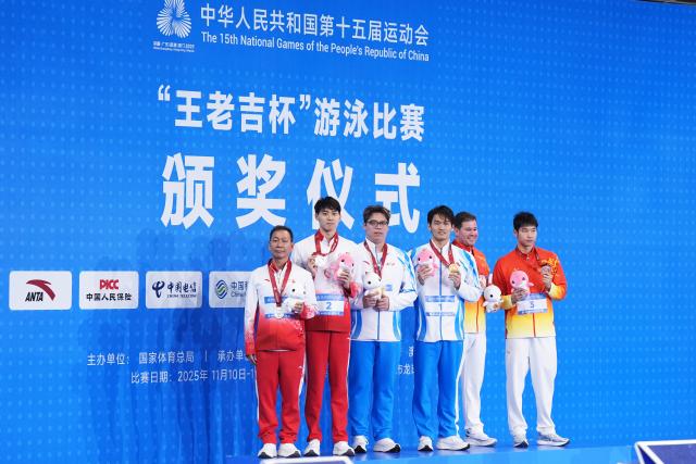 (251115) -- SHENZHEN, Nov. 15, 2025 (Xinhua) -- Gold medalist Xu Jiayu of Zhejiang, silver medalist Tao Guannan of Guangdong, bronze medalist Wang Yutian of Hubei pose with their coaches during the awarding ceremony for the men's 200m backstroke of swimming at China's 15th National Games in Shenzhen, south China's Guangdong Province, Nov. 15, 2025. (Xinhua/Du Yu)