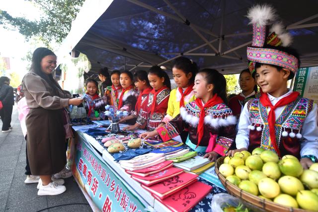 (251115) -- LIUZHOU, Nov. 15, 2025 (Xinhua) -- Students attend an agricultural fair in Rongshui Miao Autonomous County, south China's Guangxi Zhuang Autonomous Region, Nov. 15, 2025. A Miao town community of Rongshui County held this fair to showcase and promote agricultural specialties and intangible cultural heritage from neighboring townships. (Photo by Zheng Changhao/Xinhua)