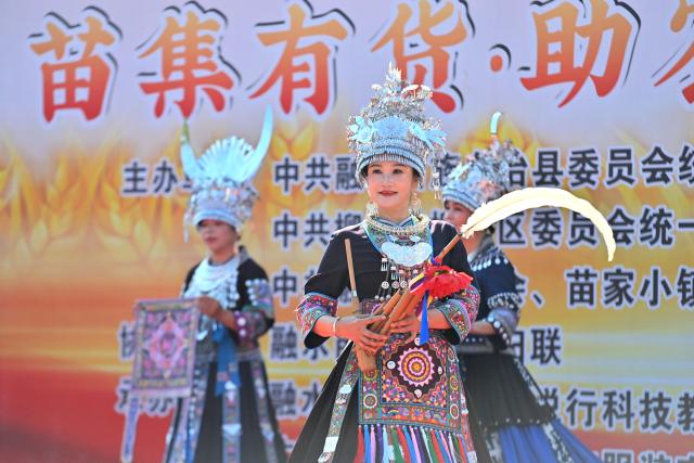 (251115) -- LIUZHOU, Nov. 15, 2025 (Xinhua) -- Actresses display embroideries of Miao ethnic group and lusheng, a traditional reed-pipe wind instrument, at an agricultural fair in Rongshui Miao Autonomous County, south China's Guangxi Zhuang Autonomous Region, Nov. 15, 2025. A Miao town community of Rongshui County held this fair to showcase and promote agricultural specialties and intangible cultural heritage from neighboring townships. (Xinhua/Huang Xiaobang)
