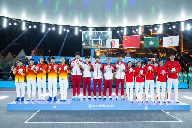 (251115) -- MACAO, Nov. 15, 2025 (Xinhua) -- Gold medalists team Shandong, silver medalists team Hubei and bronze medalists team Sichuan pose with their coaches during the awarding ceremony for women's 3x3 basketball at China's 15th National Games in Macao, south China, Nov. 15, 2025. (Xinhua/Cheong Kam Ka)