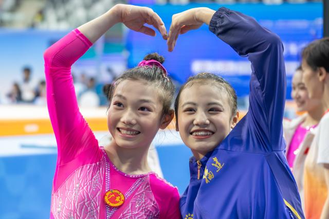 (251115) -- ZHAOQING, Nov. 15, 2025 (Xinhua) -- Ke Qinqin (L) of Guangdong and Qiu Qiyuan of Fujian greet the spectators after the artistic gymnastics women's individual all-around final at China's 15th National Games in Zhaoqing, south China's Guangdong Province, Nov. 15, 2025. (Xinhua/Du Zixuan)