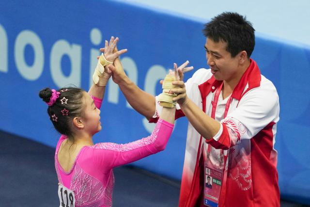 (251115) -- ZHAOQING, Nov. 15, 2025 (Xinhua) -- Ke Qinqin (L) of Guangdong celebrates with her coach during the artistic gymnastics women's individual all-around final at China's 15th National Games in Zhaoqing, south China's Guangdong Province, Nov. 15, 2025. (Xinhua/Xu Bingjie)
