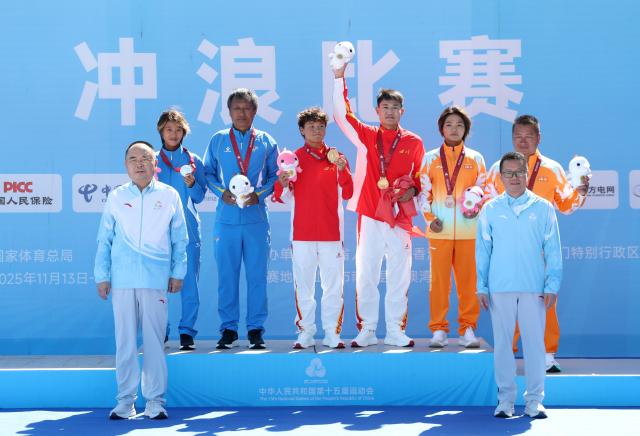 (251116) -- NAN'AO, Nov. 16, 2025 (Xinhua) -- Gold medalist Yang Siqi (3rd L, back) of Sichuan, silver medalist Jin Shuhan (1st L, back) of Liaoning and bronze medalist Deng Xueying (2nd R, back) of Hainan pose during the awarding ceremony for the women's shortboard surfing at China's 15th National Games in Nan'ao, south China's Guangdong Province, Nov. 16, 2025. (Xinhua/Lu Hanxin)