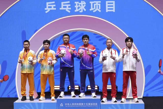 (251116) -- MACAO, Nov. 16, 2025 (Xinhua) -- Gold medalist Fan Zhendong (3rd R) of Shanghai, silver medalist Lin Shidong (2nd L) of Hainan and bronze medalist Wang Chuqin (1st R) of Beijing pose with their coaches during the awarding ceremony for the men's singles of table tennis at China's 15th National Games in Macao, south China, Nov. 16, 2025. (Xinhua/Chen Bin)