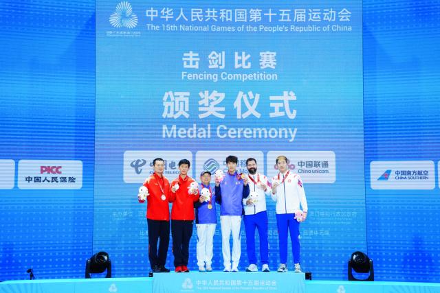 (251116) -- HONG KONG, Nov. 16, 2025 (Xinhua) -- Gold medalist Xu Jie of Fujian, silver medalist Zou Tianyi of Jiangsu and bronze medalist Cheung Ka Long of Hong Kong pose with their coaches during the awarding ceremony after the men's foil individual final of fencing at China's 15th National Games in Hong Kong, south China, Nov. 16, 2025. (Xinhua/Zhu Wei)