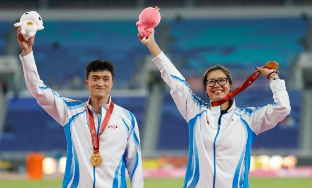 (251116) -- GUANGZHOU, Nov. 16, 2025 (Xinhua) -- Gold medalist Hua Zihui of Zhejiang and his coach wave during the awarding ceremony of the men's decathlon of athletics at China's 15th National Games in Guangzhou, south China's Guangdong Province, Nov. 16, 2025. (Xinhua/Huang Wei)