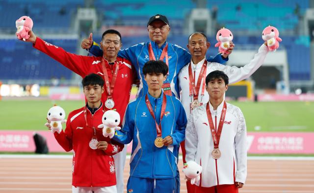 (251116) -- GUANGZHOU, Nov. 16, 2025 (Xinhua) -- Gold medalist Yu Shuiqing of Liaoning, silver medalist Chen Yongchao of Guizhou and bronze medalist Chen Wenjie of Yunnan pose with their coaches during the awarding ceremony after the men's 3000m steeplechase final of athletics at China's 15th National Games in Guangzhou, south China's Guangdong Province, Nov. 16, 2025. (Xinhua/Huang Wei)