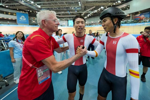 (251116) -- HONG KONG, Nov. 16, 2025 (Xinhua) -- Yang Yang (R), Li Boan (C), both from Henan, celebrate with their coach Gary John Sutton after winning the men's Madison final of cycling track at China's 15th National Games in Hong Kong, south China, Nov. 16, 2025. (Xinhua/Wu Lu)