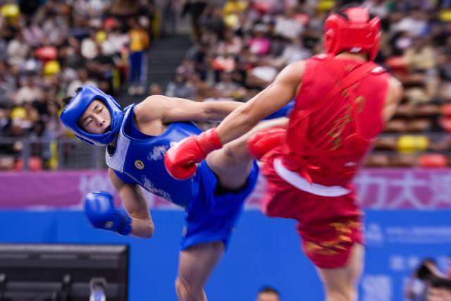 (251116) -- ZHANJIANG, Nov. 16, 2025 (Xinhua) -- Tang Sishuo (L) of Jiangsu competes with Huang Jiajun of Fujian during the wushu sanda men's 60kg final at China's 15th National Games in Zhanjiang, south China's Guangdong Province, Nov. 16, 2025. (Xinhua/Li Bo)