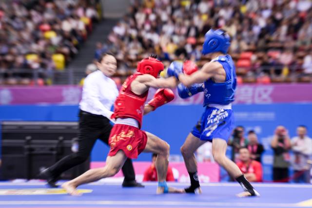 (251116) -- ZHANJIANG, Nov. 16, 2025 (Xinhua) -- Shen Guoshun (L) of Henan competes against Zhang Jingmin of Shandong during the 56kg event of wushu sanda men's team final at China's 15th National Games in Zhanjiang, south China's Guangdong Province, Nov. 16, 2025. (Xinhua/Li Bo)