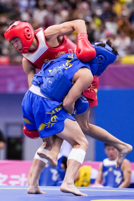 (251116) -- ZHANJIANG, Nov. 16, 2025 (Xinhua) -- Jin Wenbin (top) of Henan competes with Zhang Yuhua of Shandong during the 65kg event of wushu sanda men's team final at China's 15th National Games in Zhanjiang, south China's Guangdong Province, Nov. 16, 2025. (Xinhua/Li Bo)