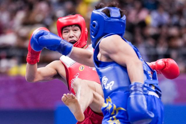 (251116) -- ZHANJIANG, Nov. 16, 2025 (Xinhua) -- Jin Wenbin (L) of Henan competes with Zhang Yuhua of Shandong during the 65kg event of wushu sanda men's team final at China's 15th National Games in Zhanjiang, south China's Guangdong Province, Nov. 16, 2025. (Xinhua/Li Bo)