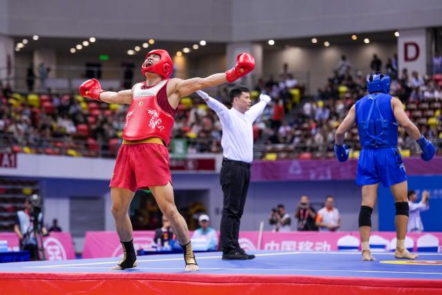 (251116) -- ZHANJIANG, Nov. 16, 2025 (Xinhua) -- Wang Shaohua (L) of Henan celebrates scoring while competing against Zhai Chenxi of Shandong during the wushu sanda men's 90kg final at China's 15th National Games in Zhanjiang, south China's Guangdong Province, Nov. 16, 2025. (Xinhua/Li Bo)