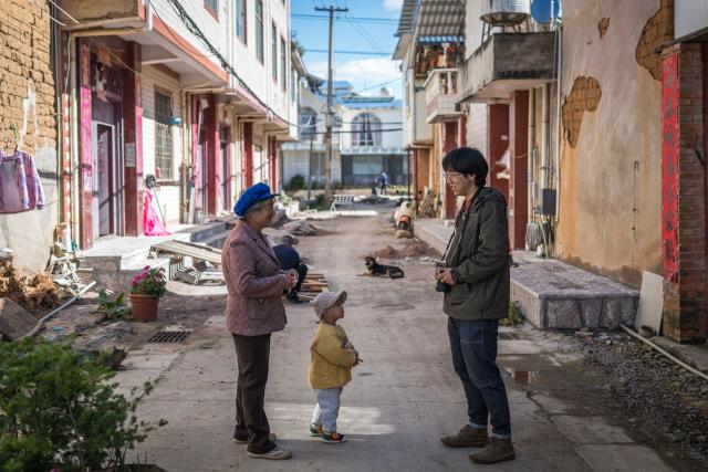 (251117) -- KUNMING, Nov. 17, 2025 (Xinhua) -- Zhang Hang (R) talks with villagers at Haiyan Village in Kunming, southwest China's Yunnan Province, Nov. 12, 2025. Zhang Hang, 32, is an inheritor of the Kunming Wamao-making technique and the founder of the Heart Chamber Wamao Museum.
   Wamao, a cat-shaped pottery artifact originating in Yunnan, combines practical design with folk beliefs. Traditionally mounted on eaves or lintels, it was believed to drive away evil spirits and bring peace to the household. In 2023, Wamao was listed as one of Yunnan's provincial intangible cultural heritage items.
   Zhang first encountered Wamao in 2012, when he was studying folk art design at Yunnan Arts University. "I was drawn to its expressive artistic form," Zhang said. "I wanted to integrate its unconstrained style into modern design."
   Since then, searching for old Wamao has become part of his daily life. He has wandered through old city markets and construction sites, from cities of Dali and Lijiang to the outskirts of Kunming, chasing traces of the clay guardians.
   In 2019, Zhang founded the Wamao museum to promote the craft through exhibitions, hands-on classes, and cultural tours. Visitors can take part in Wamao-making workshops, Wamao placement ceremonies, and field trips to traditional villages.
   In his studio, Zhang mixes clay, shapes the cat's head and body, and then fires it in a kiln after drying. The belly of the cat is left hollow, with its mouth and tail connected, symbolizing the idea of "swallowing evil and releasing blessings."
   Skilled artisans can complete a Wamao in a week, but Zhang said the true challenge lies in merging tradition with innovation.
   "It sometimes takes a month to create one that feels right," he said. "The goal is to help this ancient craft find new meaning in modern society."
   As urbanization changes the landscape of Kunming, many old houses have disappeared. Zhang hopes his work will help preserve the memory of the Wamao and its cultural spirit.
   "As old houses crumble, I hope the chamber of my heart will serve as a new home for Wamao," he said. (Xinhua/Wang Guansen)