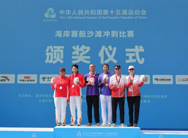(251117) -- YANGJIANG, Nov. 17, 2025 (Xinhua) -- Gold medalist Tan Rukai (3rd R) of Fujian, silver medalist Long Zhentao (2nd L) of Sichuan, bronze medalist Liu Jiayu (2nd R) pose with their coaches during the awarding ceremony for the men's single sculls of coastal rowing at China's 15th National Games in Yangjiang, south China's Guangdong Province, Nov. 17, 2025. (Xinhua/Li Ran)