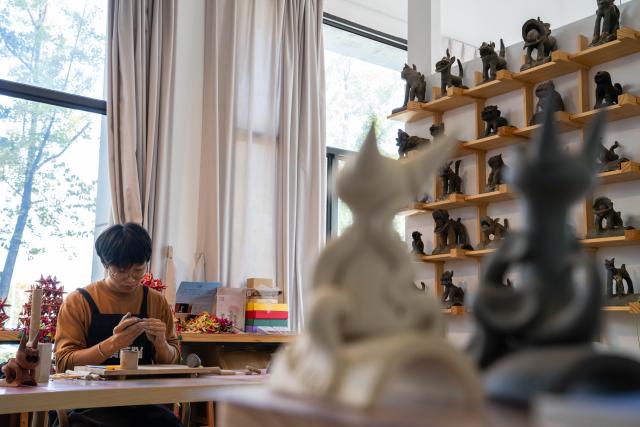 (251117) -- KUNMING, Nov. 17, 2025 (Xinhua) -- Zhang Hang makes Wamao at the Heart Chamber Wamao Museum in Kunming, southwest China's Yunnan Province, Nov. 7, 2025. Zhang Hang, 32, is an inheritor of the Kunming Wamao-making technique and the founder of the Heart Chamber Wamao Museum.
   Wamao, a cat-shaped pottery artifact originating in Yunnan, combines practical design with folk beliefs. Traditionally mounted on eaves or lintels, it was believed to drive away evil spirits and bring peace to the household. In 2023, Wamao was listed as one of Yunnan's provincial intangible cultural heritage items.
   Zhang first encountered Wamao in 2012, when he was studying folk art design at Yunnan Arts University. "I was drawn to its expressive artistic form," Zhang said. "I wanted to integrate its unconstrained style into modern design."
   Since then, searching for old Wamao has become part of his daily life. He has wandered through old city markets and construction sites, from cities of Dali and Lijiang to the outskirts of Kunming, chasing traces of the clay guardians.
   In 2019, Zhang founded the Wamao museum to promote the craft through exhibitions, hands-on classes, and cultural tours. Visitors can take part in Wamao-making workshops, Wamao placement ceremonies, and field trips to traditional villages.
   In his studio, Zhang mixes clay, shapes the cat's head and body, and then fires it in a kiln after drying. The belly of the cat is left hollow, with its mouth and tail connected, symbolizing the idea of "swallowing evil and releasing blessings."
   Skilled artisans can complete a Wamao in a week, but Zhang said the true challenge lies in merging tradition with innovation.
   "It sometimes takes a month to create one that feels right," he said. "The goal is to help this ancient craft find new meaning in modern society."
   As urbanization changes the landscape of Kunming, many old houses have disappeared. Zhang hopes his work will help preserve the memory of the Wamao and its cultural spirit.
   "As old houses crumble, I hope the chamber of my heart will serve as a new home for Wamao," he said. (Xinhua/Gao Yongwei)