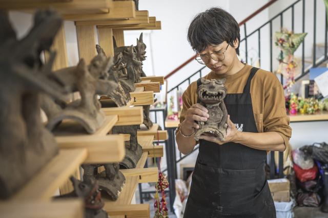 (251117) -- KUNMING, Nov. 17, 2025 (Xinhua) -- Zhang Hang works at the Heart Chamber Wamao Museum in Kunming, southwest China's Yunnan Province, Nov. 7, 2025. Zhang Hang, 32, is an inheritor of the Kunming Wamao-making technique and the founder of the Heart Chamber Wamao Museum.
   Wamao, a cat-shaped pottery artifact originating in Yunnan, combines practical design with folk beliefs. Traditionally mounted on eaves or lintels, it was believed to drive away evil spirits and bring peace to the household. In 2023, Wamao was listed as one of Yunnan's provincial intangible cultural heritage items.
   Zhang first encountered Wamao in 2012, when he was studying folk art design at Yunnan Arts University. "I was drawn to its expressive artistic form," Zhang said. "I wanted to integrate its unconstrained style into modern design."
   Since then, searching for old Wamao has become part of his daily life. He has wandered through old city markets and construction sites, from cities of Dali and Lijiang to the outskirts of Kunming, chasing traces of the clay guardians.
   In 2019, Zhang founded the Wamao museum to promote the craft through exhibitions, hands-on classes, and cultural tours. Visitors can take part in Wamao-making workshops, Wamao placement ceremonies, and field trips to traditional villages.
   In his studio, Zhang mixes clay, shapes the cat's head and body, and then fires it in a kiln after drying. The belly of the cat is left hollow, with its mouth and tail connected, symbolizing the idea of "swallowing evil and releasing blessings."
   Skilled artisans can complete a Wamao in a week, but Zhang said the true challenge lies in merging tradition with innovation.
   "It sometimes takes a month to create one that feels right," he said. "The goal is to help this ancient craft find new meaning in modern society."
   As urbanization changes the landscape of Kunming, many old houses have disappeared. Zhang hopes his work will help preserve the memory of the Wamao and its cultural spirit.
   "As old houses crumble, I hope the chamber of my heart will serve as a new home for Wamao," he said. (Xinhua/Wang Guansen)