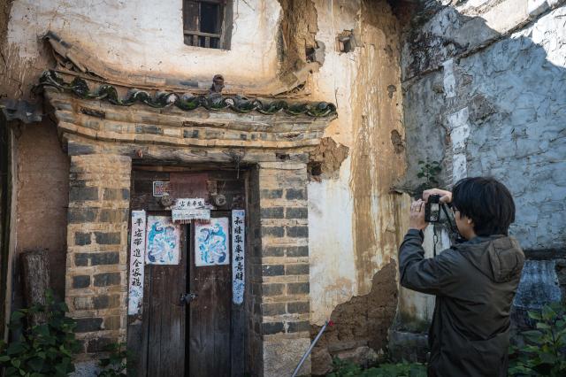 (251117) -- KUNMING, Nov. 17, 2025 (Xinhua) -- Zhang Hang collects images of Wamao with his camera at Haiyan Village in Kunming, southwest China's Yunnan Province, Nov. 12, 2025. Zhang Hang, 32, is an inheritor of the Kunming Wamao-making technique and the founder of the Heart Chamber Wamao Museum.
   Wamao, a cat-shaped pottery artifact originating in Yunnan, combines practical design with folk beliefs. Traditionally mounted on eaves or lintels, it was believed to drive away evil spirits and bring peace to the household. In 2023, Wamao was listed as one of Yunnan's provincial intangible cultural heritage items.
   Zhang first encountered Wamao in 2012, when he was studying folk art design at Yunnan Arts University. "I was drawn to its expressive artistic form," Zhang said. "I wanted to integrate its unconstrained style into modern design."
   Since then, searching for old Wamao has become part of his daily life. He has wandered through old city markets and construction sites, from cities of Dali and Lijiang to the outskirts of Kunming, chasing traces of the clay guardians.
   In 2019, Zhang founded the Wamao museum to promote the craft through exhibitions, hands-on classes, and cultural tours. Visitors can take part in Wamao-making workshops, Wamao placement ceremonies, and field trips to traditional villages.
   In his studio, Zhang mixes clay, shapes the cat's head and body, and then fires it in a kiln after drying. The belly of the cat is left hollow, with its mouth and tail connected, symbolizing the idea of "swallowing evil and releasing blessings."
   Skilled artisans can complete a Wamao in a week, but Zhang said the true challenge lies in merging tradition with innovation.
   "It sometimes takes a month to create one that feels right," he said. "The goal is to help this ancient craft find new meaning in modern society."
   As urbanization changes the landscape of Kunming, many old houses have disappeared. Zhang hopes his work will help preserve the memory of the Wamao and its cultural spirit.
   "As old houses crumble, I hope the chamber of my heart will serve as a new home for Wamao," he said. (Xinhua/Wang Guansen)
