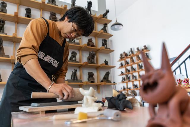 (251117) -- KUNMING, Nov. 17, 2025 (Xinhua) -- Zhang Hang makes Wamao at the Heart Chamber Wamao Museum in Kunming, southwest China's Yunnan Province, Nov. 7, 2025. Zhang Hang, 32, is an inheritor of the Kunming Wamao-making technique and the founder of the Heart Chamber Wamao Museum.
   Wamao, a cat-shaped pottery artifact originating in Yunnan, combines practical design with folk beliefs. Traditionally mounted on eaves or lintels, it was believed to drive away evil spirits and bring peace to the household. In 2023, Wamao was listed as one of Yunnan's provincial intangible cultural heritage items.
   Zhang first encountered Wamao in 2012, when he was studying folk art design at Yunnan Arts University. "I was drawn to its expressive artistic form," Zhang said. "I wanted to integrate its unconstrained style into modern design."
   Since then, searching for old Wamao has become part of his daily life. He has wandered through old city markets and construction sites, from cities of Dali and Lijiang to the outskirts of Kunming, chasing traces of the clay guardians.
   In 2019, Zhang founded the Wamao museum to promote the craft through exhibitions, hands-on classes, and cultural tours. Visitors can take part in Wamao-making workshops, Wamao placement ceremonies, and field trips to traditional villages.
   In his studio, Zhang mixes clay, shapes the cat's head and body, and then fires it in a kiln after drying. The belly of the cat is left hollow, with its mouth and tail connected, symbolizing the idea of "swallowing evil and releasing blessings."
   Skilled artisans can complete a Wamao in a week, but Zhang said the true challenge lies in merging tradition with innovation.
   "It sometimes takes a month to create one that feels right," he said. "The goal is to help this ancient craft find new meaning in modern society."
   As urbanization changes the landscape of Kunming, many old houses have disappeared. Zhang hopes his work will help preserve the memory of the Wamao and its cultural spirit.
   "As old houses crumble, I hope the chamber of my heart will serve as a new home for Wamao," he said. (Xinhua/Gao Yongwei)
