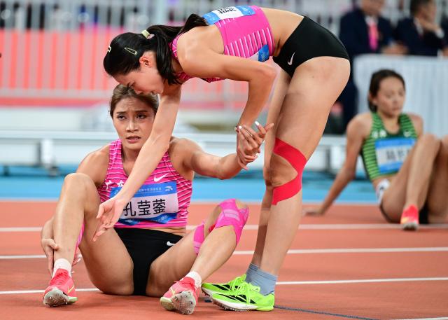 (251117) -- GUANGZHOU, Nov. 17, 2025 (Xinhua) -- Mo Jiadie (R) of Guangdong helps her teammate Kong Yingying after the women's 400m hurdles final of athletics at China's 15th National Games in Guangzhou, south China's Guangdong Province, Nov. 17, 2025. (Xinhua/Jiang Han)