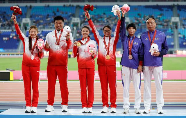 (251117) -- GUANGZHOU, Nov. 17, 2025 (Xinhua) -- Gold medalist Mo Jiadie of Guangdong, silver medalist Kong Yingying of Guangdong and bronze medalist Ou Ying of Fujian and their coaches pose during the awarding ceremony of the women's 400m hurdles of athletics at China's 15th National Games in Guangzhou, south China's Guangdong Province, Nov. 17, 2025. (Xinhua/Huang Wei)