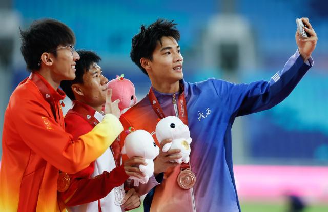 (251117) -- GUANGZHOU, Nov. 17, 2025 (Xinhua) -- Gold medalist Li Zeyang of Hubei, silver medalist Wang Shengjie of Shandong and bronze medalist Zeng Keli of Guangxi pose for a selfie after the awarding ceremony for the men's 100m of athletics at China's 15th National Games in Guangzhou, south China's Guangdong Province, Nov. 17, 2025. (Xinhua/Huang Wei)