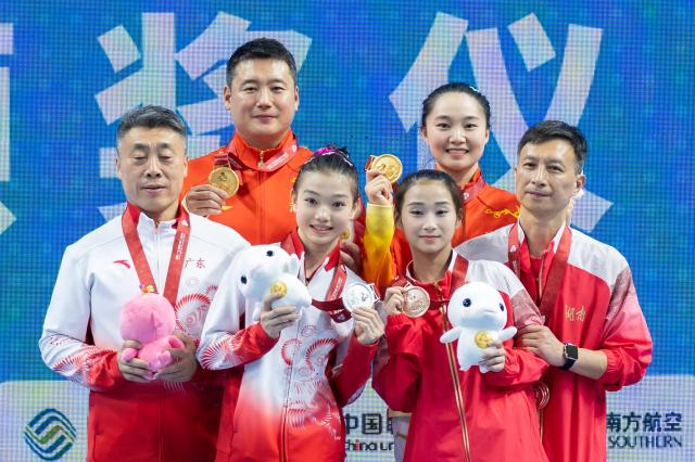 (251117) -- ZHAOQING, Nov. 17, 2025 (Xinhua) -- Gold medalist Zhao Jiayi of Hubei, silver medalist Ke Qinqin of Guangdong and bronze medalist Zhang Qi of Hunan pose with their coaches during the awarding ceremony for the artistic gymnastics women's floor exercise at China's 15th National Games in Zhaoqing, south China's Guangdong Province, Nov. 17, 2025. (Xinhua/Du Zixuan)