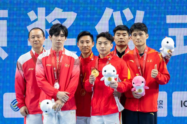 (251117) -- ZHAOQING, Nov. 17, 2025 (Xinhua) -- Gold medalist Zou Jingyuan of Sichuan, silver medalist Zhang Boheng of Hunan and bronze medalist Shi Cong of Jiangsu pose with their coaches during the awarding ceremony for the artistic gymnastics men's parallel bars at China's 15th National Games in Zhaoqing, south China's Guangdong Province, Nov. 17, 2025. (Xinhua/Du Zixuan)