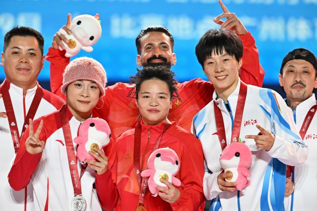 (251118) -- GUANGZHOU, Nov. 18, 2025 (Xinhua) -- Gold medalist Liu Qingyi of Henan, silver medalist Guo Pu of Shandong and bronze medalist Zeng Yingying of Zhejiang pose with their coaches during the awarding ceremony for breaking B-Girls at China's 15th National Games in Guangzhou, south China's Guangdong Province, Nov. 18, 2025. (Xinhua/Xiao Yijiu)