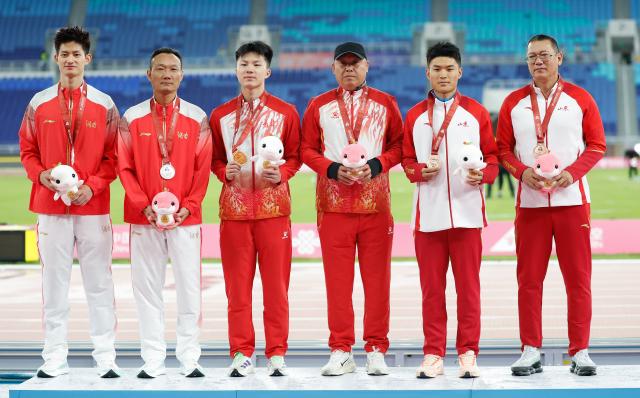 (251118) -- GUANGZHOU, Nov. 18, 2025 (Xinhua) -- Gold medalist Shu Heng of Jilin, silver medalist Zhang Mingkun of Hunan and bronze medalist Gao Peiqi of Shandong pose with their coaches during the awarding ceremony for the men's long jump of athletics at China's 15th National Games in Guangzhou, south China's Guangdong Province, Nov. 18, 2025. (Xinhua/Huang Wei)