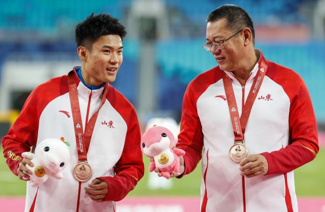 (251118) -- GUANGZHOU, Nov. 18, 2025 (Xinhua) -- Bronze medalist Gao Peiqi of Shandong and his coach are seen during the awarding ceremony for the men's long jump of athletics at China's 15th National Games in Guangzhou, south China's Guangdong Province, Nov. 18, 2025. (Xinhua/Huang Wei)