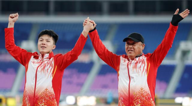 (251118) -- GUANGZHOU, Nov. 18, 2025 (Xinhua) -- Gold medalist Shu Heng of Jilin and his coach wave during the awarding ceremony for the men's long jump of athletics at China's 15th National Games in Guangzhou, south China's Guangdong Province, Nov. 18, 2025. (Xinhua/Huang Wei)