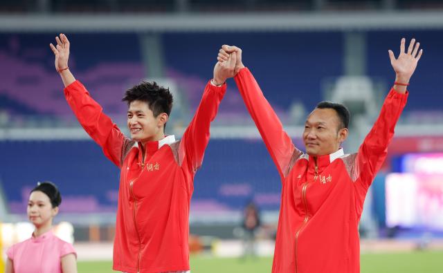 (251118) -- GUANGZHOU, Nov. 18, 2025 (Xinhua) -- Silver medalist Zhang Mingkun of Hunan and his coach wave during the awarding ceremony for the men's long jump of athletics at China's 15th National Games in Guangzhou, south China's Guangdong Province, Nov. 18, 2025. (Xinhua/Huang Wei)