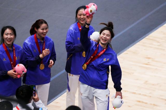 (251118) -- HONG KONG, Nov. 18, 2025 (Xinhua) -- Lin Sheng (1st R) of Fujian throws a mascot to spectators after the awarding ceremony for women's team epee of fencing at China's 15th National Games in Hong Kong, south China, Nov. 18, 2025. (Xinhua/Zhu Wei)