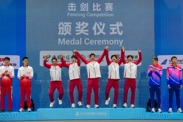 (251118) -- HONG KONG, Nov. 18, 2025 (Xinhua) -- Gold medalists team Shandong and their coach react during the awarding ceremony for men's team sabre of fencing at China's 15th National Games in Hong Kong, south China, Nov. 18, 2025. (Xinhua/Wu Lu)