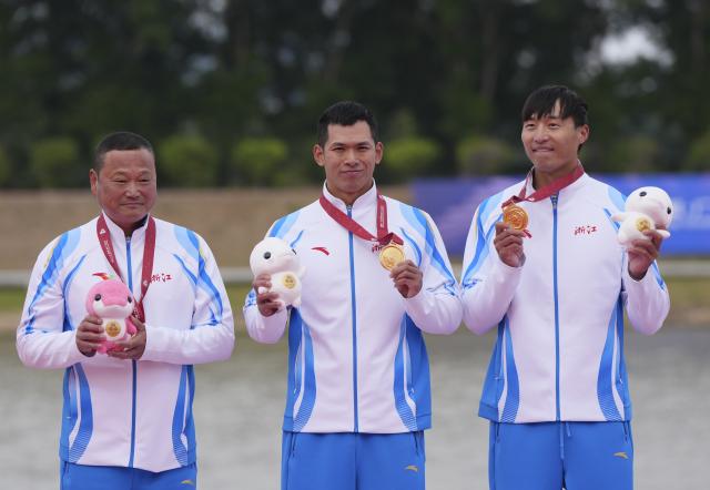(251119) -- GUANGZHOU, Nov. 19, 2025 (Xinhua) -- Gold medalists Wang Congkang (C)/Xu Jiawei (R) of Zhejiang pose with their coach during the awarding ceremony for the men's kayak double 500m of canoe sprint at China's 15th National Games in Guangzhou, south China's Guangdong Province, Nov. 19, 2025. (Xinhua/Jigme Dorji)
