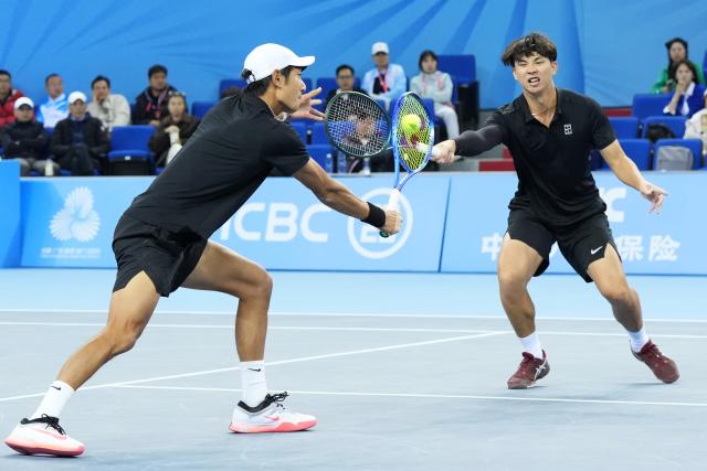 (251119) -- HENGQIN, Nov. 19, 2025 (Xinhua) -- Tang Sheng/Sun Qian (L) compete during the tennis men's doubles final between Tang Sheng/Sun Qian of Jiangsu and Bu Yunchaokete/Zheng Zhan of Zhejiang at China's 15th National Games in Hengqin, south China's Guangdong Province, Nov. 19, 2025. (Xinhua/Yan Linyun)