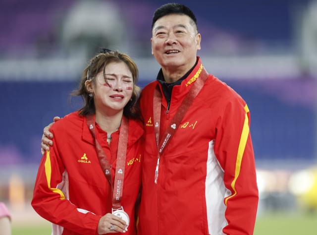 (251119) -- GUANGZHOU, Nov. 19, 2025 (Xinhua) -- Silver medalist Wu Yanni of Sichuan and her coach pose during the awarding ceremony for the women's 100m hurdles of athletics at China's 15th National Games in Guangzhou, south China's Guangdong Province, Nov. 19, 2025. (Xinhua/Zhou Mu)