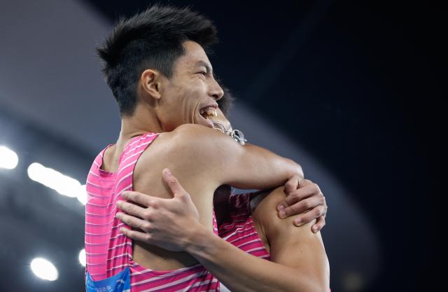 (251119) -- GUANGZHOU, Nov. 19, 2025 (Xinhua) -- Shi Junhao (R) of Shanghai hugs his teammate Lin Jianhao after the men's 200m final of athletics at China's 15th National Games in Guangzhou, south China's Guangdong Province, Nov. 19, 2025. (Xinhua/Huang Wei)