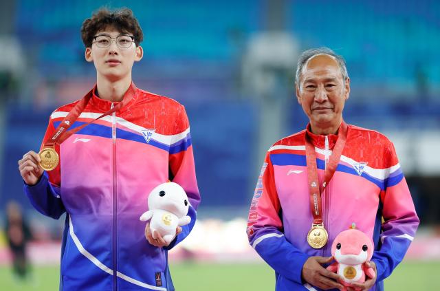 (251119) -- GUANGZHOU, Nov. 19, 2025 (Xinhua) -- Gold medalist Xu Zhuoyi (L) of Shanghai poses with his coach Sun Haiping during the awarding ceremony for the men's 110m hurdles of athletics at China's 15th National Games in Guangzhou, south China's Guangdong Province, Nov. 19, 2025. (Xinhua/Huang Wei)