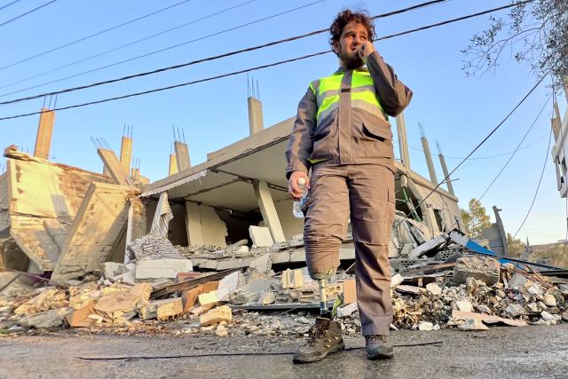 (251120) -- DEIR KIFA, Nov. 20, 2025 (Xinhua) -- A medical worker with a prosthetic limb stands in front of the ruins of a building destroyed by Israeli airstrikes in Deir Kifa, southern Lebanon, Nov. 19, 2025. (Photo by Ali Hashisho/Xinhua)