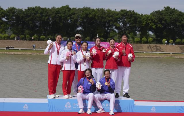 (251120) -- GUANGZHOU, Nov. 20, 2025 (Xinhua) -- Gold medalists Lin Xialian (front L)/Lin Wenjun (front R) of Fujian, silver medalists Zhang Miao (back 4th L)/Yan Hongyan (back 2nd L) of Yunnan, bronze medalists Yang Li (back 3rd R)/Yu Shifen (back 2nd R) of Guizhou pose with their coaches during the awarding ceremony for women's canoe double 200m of canoe sprint at China's 15th National Games in Guangzhou, south China's Guangdong Province, Nov. 20, 2025. (Xinhua/Jigme Dorji)