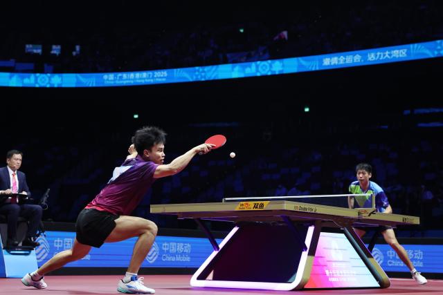 (251120) -- MACAO, Nov. 20, 2025 (Xinhua) -- Zhou Qihao (L) of Guangdong hits a return in the match against Wei Shihao of Heilongjiang during the men's team bronze medal match of table tennis between Guangdong and Heilongjiang at China's 15th National Games in Macao, south China, Nov. 20, 2025. (Xinhua/Chen Bin)
