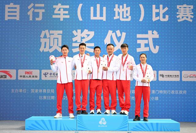 (251120) -- JIANGMEN, Nov. 20, 2025 (Xinhua) -- Gold medalist Lyu Xianjing (3rd L) of Yunnan, silver medalist Yuan Jinwei (1st L) of Yunnan, bronze medalist He Xuehui (2nd R) of Yunnan pose with their coaches during the awarding ceremony for the men's cross-country of cycling mountain bike in Jiangmen, south China's Guangdong Province, Nov. 20, 2025. (Xinhua/Chen Zhonghao)